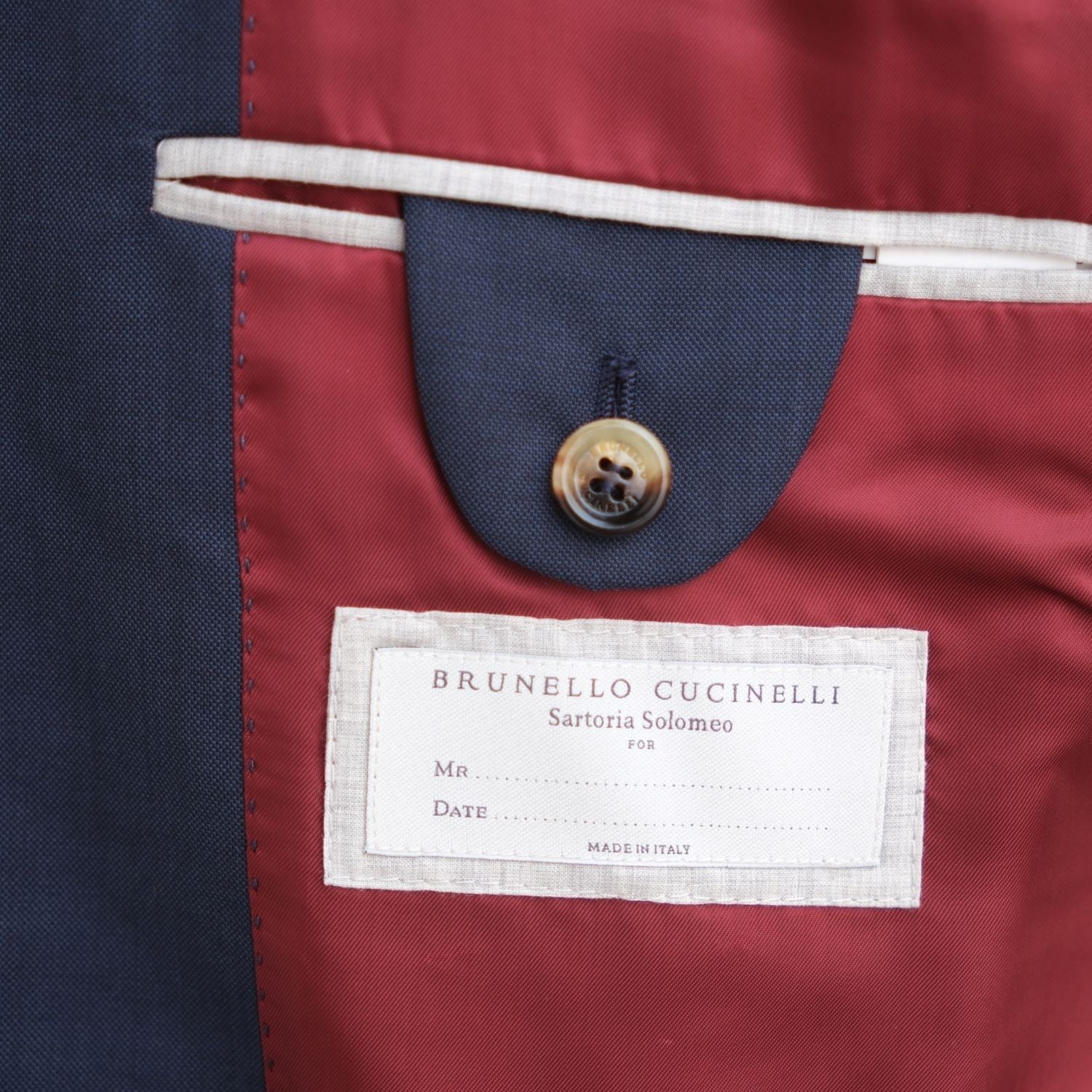 Close-up of the interior chest pocket with the Brunello Cucinelli Sartoria Solomeo label and button