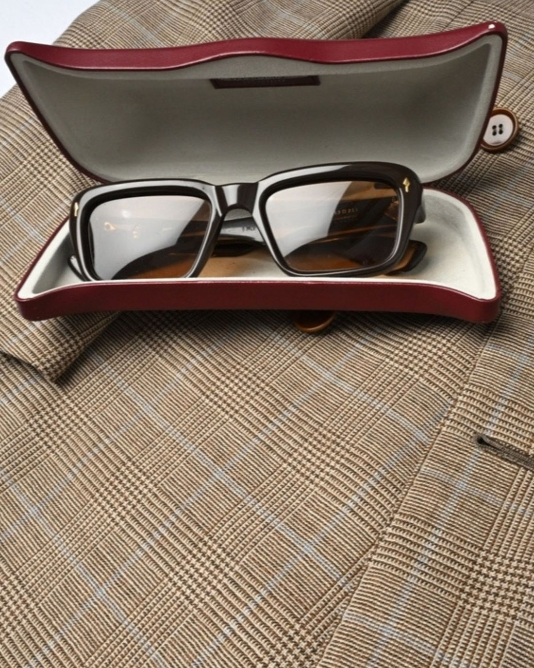 Sunglasses in leather case on Prince of Wales check jacket