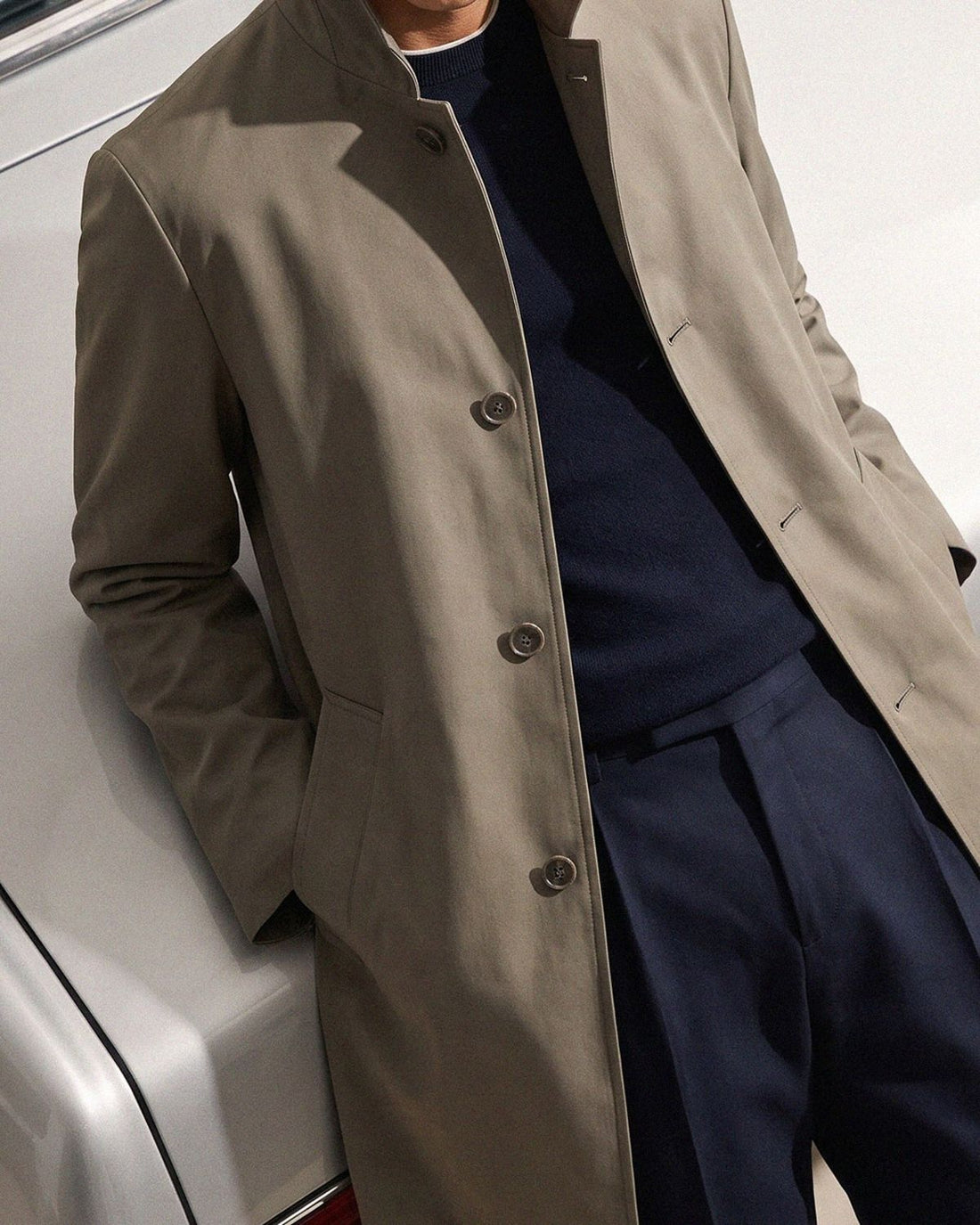 Stand-collar coat over navy knit and pleated trousers